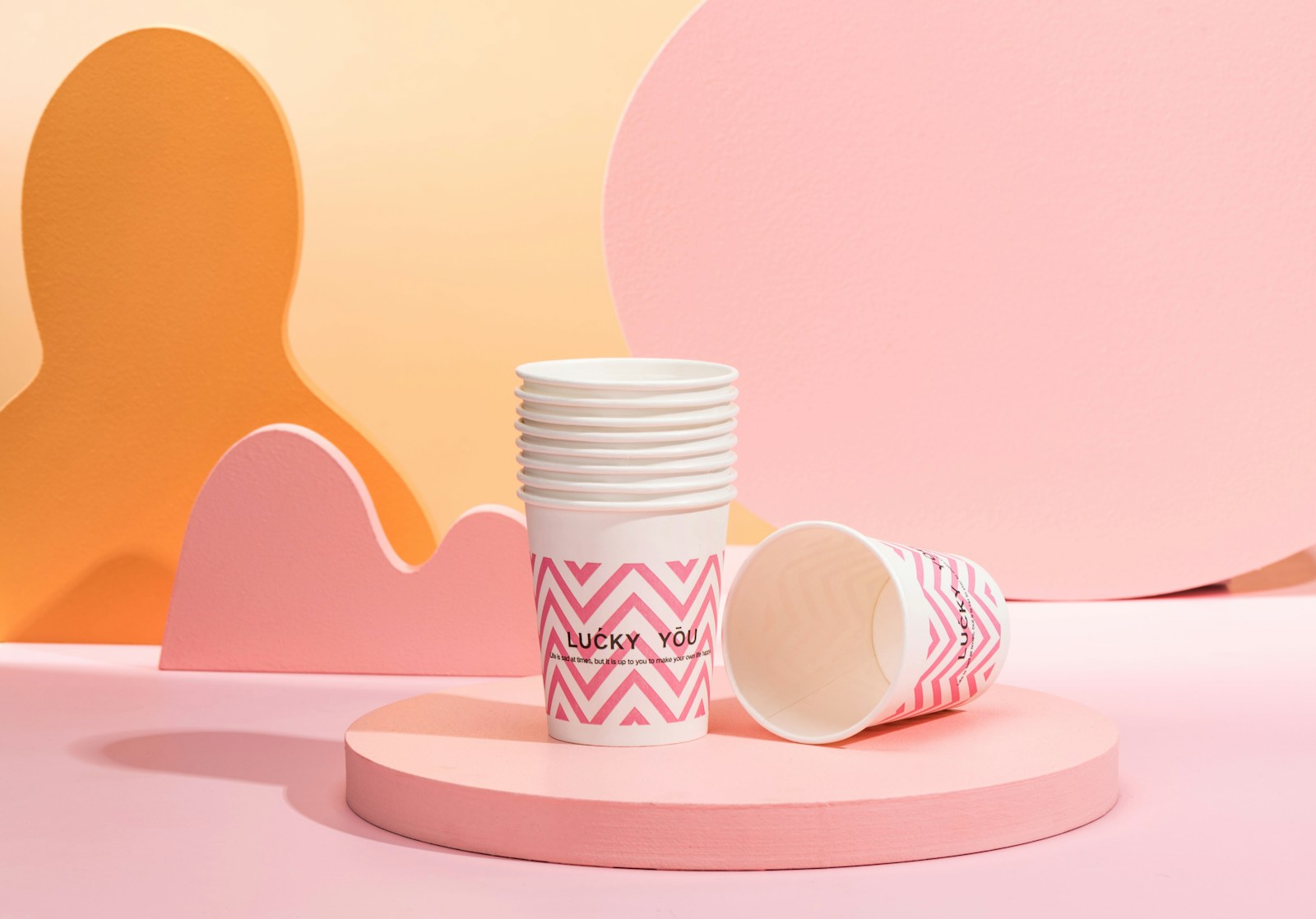 a stack of white cups sitting on top of a pink table