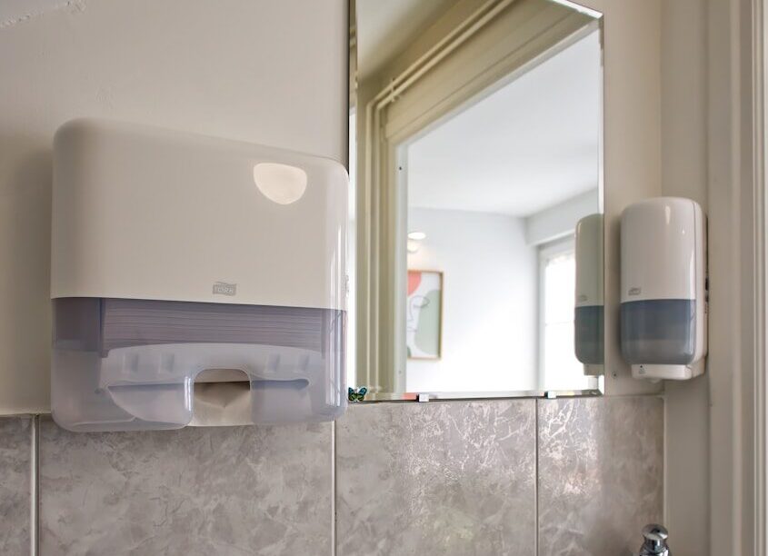 A small sink with soap and paper towel dispensers.