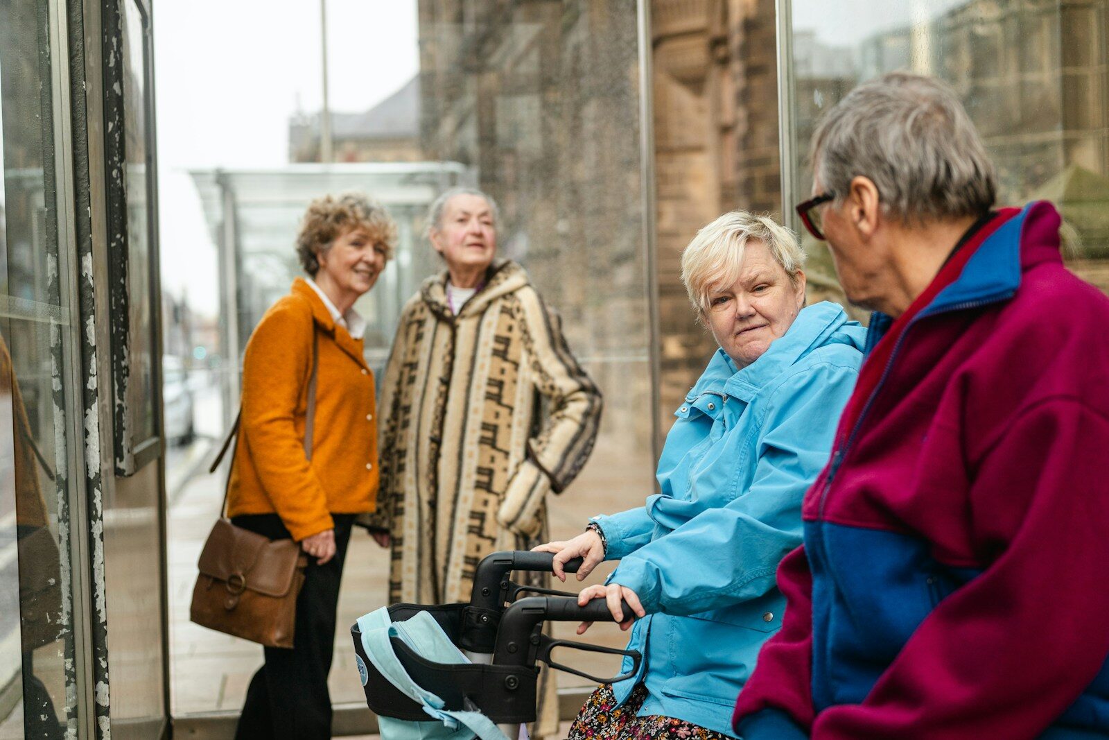 Four elderly friends waiting at a bus stop